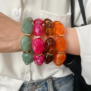 Detailed view of four colorful acrylic irregular geometric oval bracelets worn on a wrist