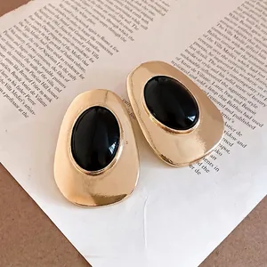 Vintage gold metal oval stud earrings with black resin inlay in minimalist style