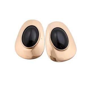Vintage gold metal stud earrings with large oval black resin centers in minimalist style