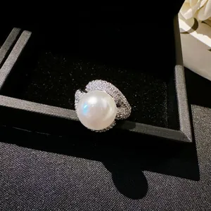 Close-up view of the elegant pearl and zircon encrusted open ring in a jewelry box.