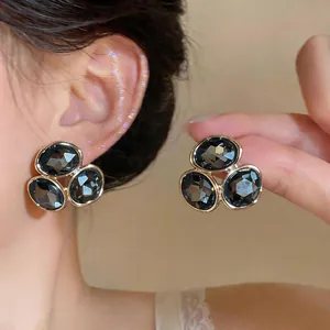 Gros plan de boucles d'oreilles élégantes en alliage avec de grands cristaux gris en triade.