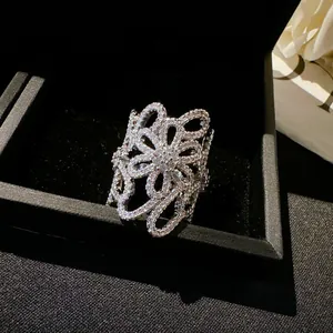 Close-up of elegant silver hollow flower ring with white zircons in a black box.