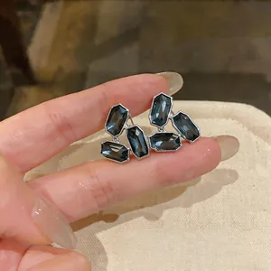 Gros plan de boucles d'oreilles élégantes avec cristaux gris foncé et alliage argenté.