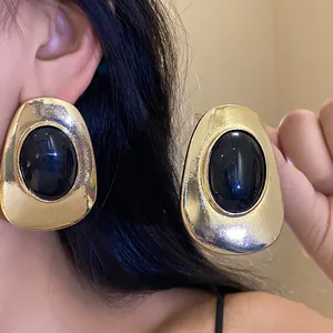 Close-up of vintage golden metal oval stud earrings with black resin inlay