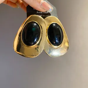 Detailed view of luxury vintage gold-tone oval earrings with black resin stone.