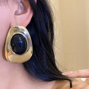 Vintage style oval gold metal stud earrings featuring a glossy black resin center stone
