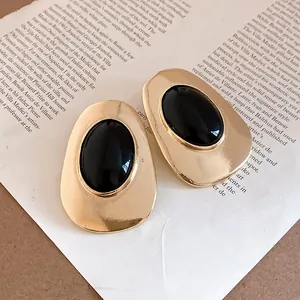 Detailed macro shot of vintage gold oval earrings with black resin inlay on paper
