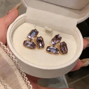 Détail de boucles d'oreilles de luxe en cristal octogonal violet dans une boîte cadeau.