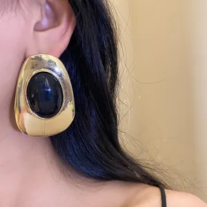 Detailed view of a vintage style gold metal earring featuring a black oval resin stone