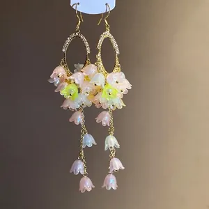 Elegant gold-toned oval hoop earrings with rhinestone accents and pink floral tassels