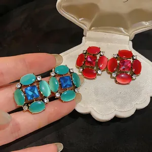Close-up of vintage cat-eye stone earrings with sparkling rhinestones in blue and red