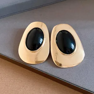 Close-up view of vintage gold metal stud earrings with oval black resin centers