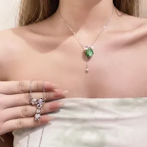 Elegant stainless steel necklace with green resin grape pendant and floral charms.