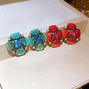Detailed view of vintage exaggerated stud earrings with cat eye stones and sparkling crystals