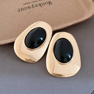 Vintage gold metal oval stud earrings with smooth black resin stone inlay detail view