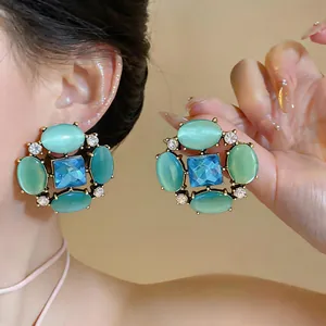 Detail view of retro oversized stud earrings with turquoise cat eye stones and blue crystal