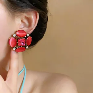 Vintage red cat-eye stone stud earrings worn by model showing exaggerated design