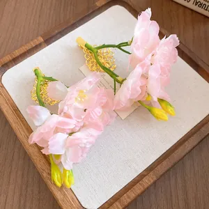 Détail de pinces à cheveux fleurs en tissu rose avec clips bec de canard en filigrane doré.