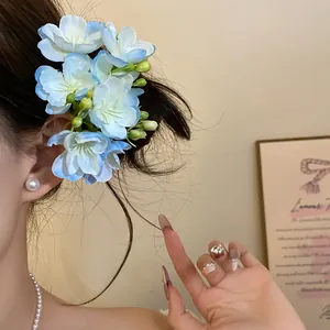 Détail d'une pince à cheveux fleur en tissu bleu clair sur modèle