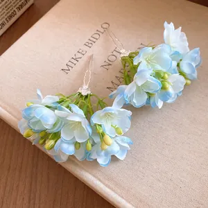 Gros plan de barrettes à fleurs en tissu bleu clair avec bourgeons jaunes sur livre beige