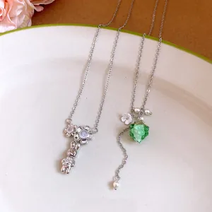 Macro detail of stainless steel necklaces with rabbit, flower, and green resin grape charms