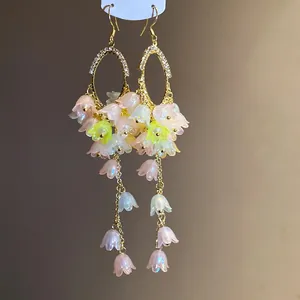 Detailed macro shot of floral tassel earrings with sparkling rhinestones and pastel flowers.