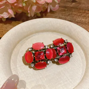 Close-up of vintage red cat-eye stone earrings with rhinestone accents in a rustic setting