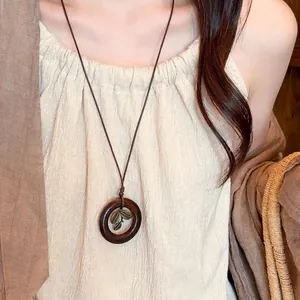 Vintage ethnic style long necklace with circular dark wood pendant and leaf detail