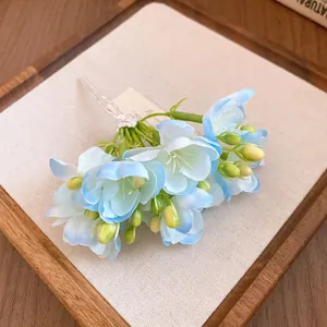 Vue détaillée d'une pince à cheveux en fleurs de tissu bleu et blanc avec boutons.