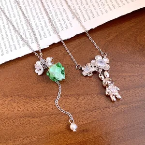 Detailed macro view of stainless steel necklaces with resin grape and rabbit charms.