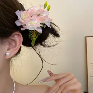 Vue détaillée de l'élégante pince à cheveux fleur en tissu rose portée sur les cheveux