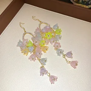 Detailed macro view of colorful acrylic flower tassel earrings with pearls and crystals