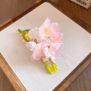 Vue détaillée d'une pince à cheveux fleurie en tissu rose avec base en filigrane doré