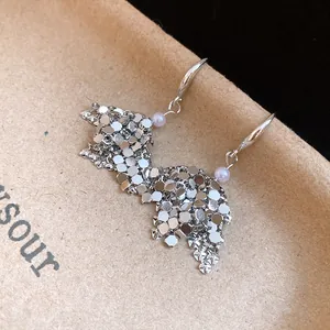 Detail view of geometric silver sequin drop earrings with light purple pearl accents