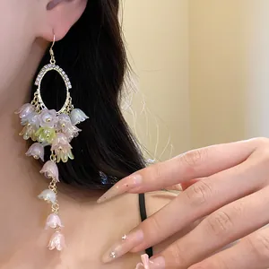 Detail shot of elegant floral tassel earrings featuring sparkling rhinestones on model.