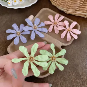 Dettaglio di orecchini a fiore pieghettati colorati in verde lime, rosa e viola.