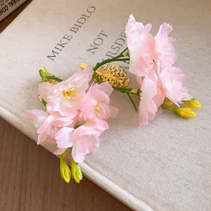 Détail en gros plan de barrettes à fleurs en tissu rose avec pinces bec de canard dorées.