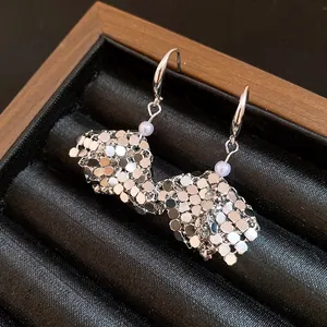 Close-up detail of silver geometric hexagonal sequin earrings with small purple beads