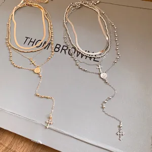 Detail view of gold and silver multi-layer necklaces with sparkling rhinestone cross pendants