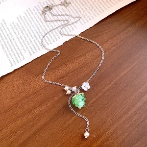 Detailed view of stainless steel necklace featuring resin grape pendant and white pearls