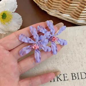 Primo piano di grandi orecchini a lobo a forma di fiore viola con centro di fiori rosa