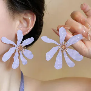 Primo piano di grandi orecchini a forma di fiore plissettato viola con dettagli dorati.