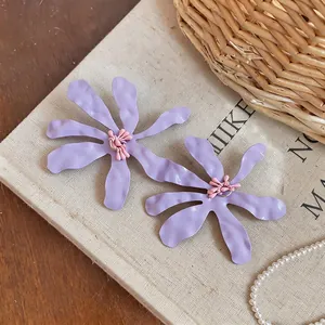 Vista macro di grandi orecchini a fiore pieghettati lavanda con dettagli rosa tenero