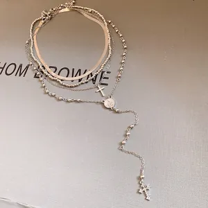 Macro view of a silver-toned multi-layered necklace featuring rhinestone cross charms