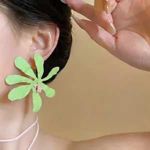 Primo piano di orecchini a forma di fiore stropicciato verde chiaro su modella