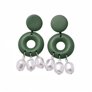 Orecchini pendenti in legno verde con nappe di perle bianche su sfondo bianco puro