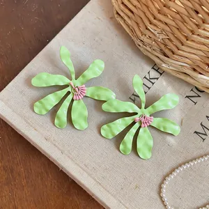 Vista dettagliata di orecchini a fiore stropicciati verde lime con stami rosa su lino