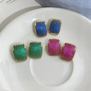 Detailed macro view of geometric zircon stud earrings in blue, green, and pink hues