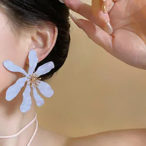 Dettaglio di un orecchino a fiore viola chiaro con petali stropicciati e un centro dorato