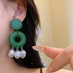 Dettaglio elegante di orecchini a cerchio in legno verde con perle barocche pendenti